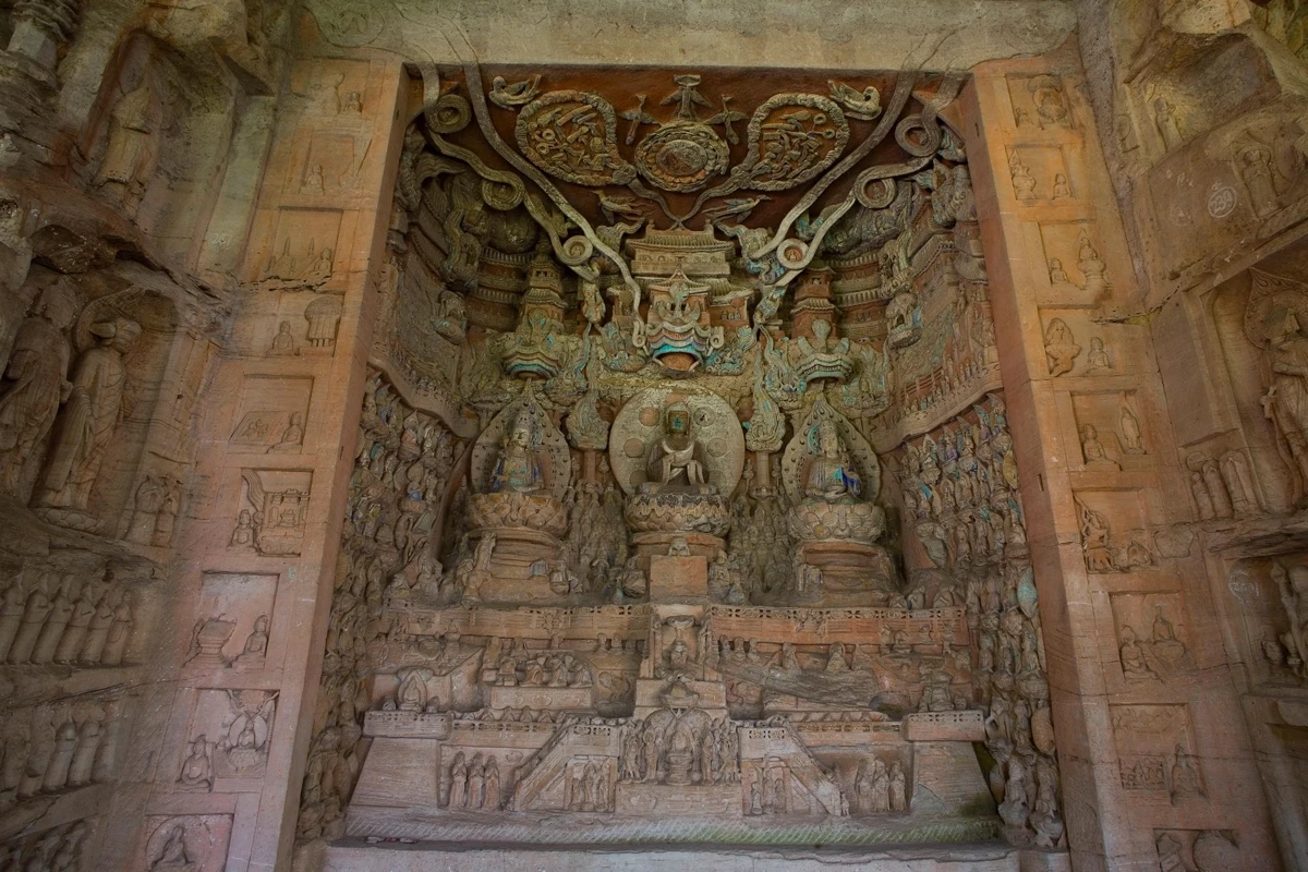 Elaborate multi-tiered carved panel with a central Buddha figure surrounded by scrollwork and architectural elements, showcasing the narrative carving tradition