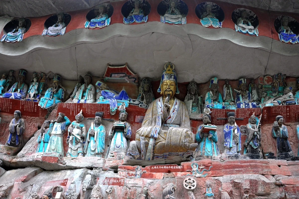 A grand multi-figure carving scene with central deity surrounded by colorful painted figures in alcoves and tiers