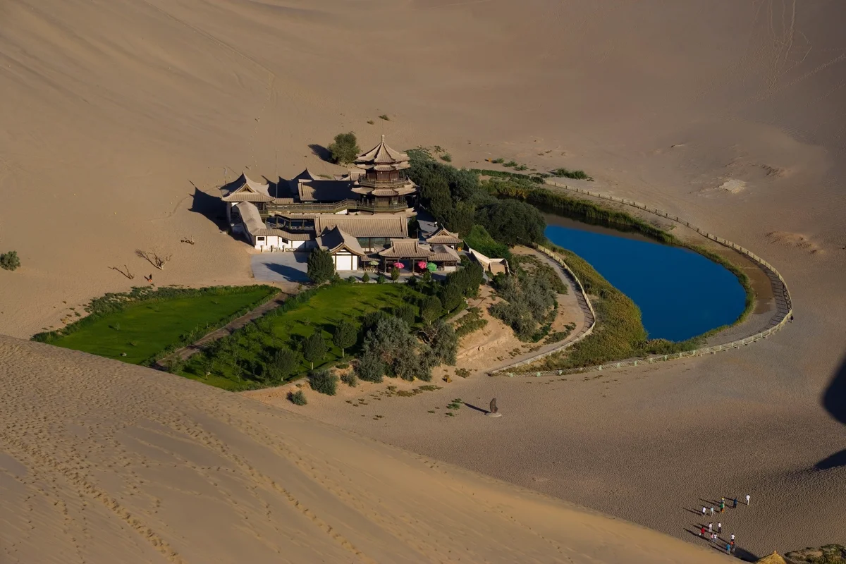 Camel caravan crossing the golden sand dunes of Mingsha Mountain
