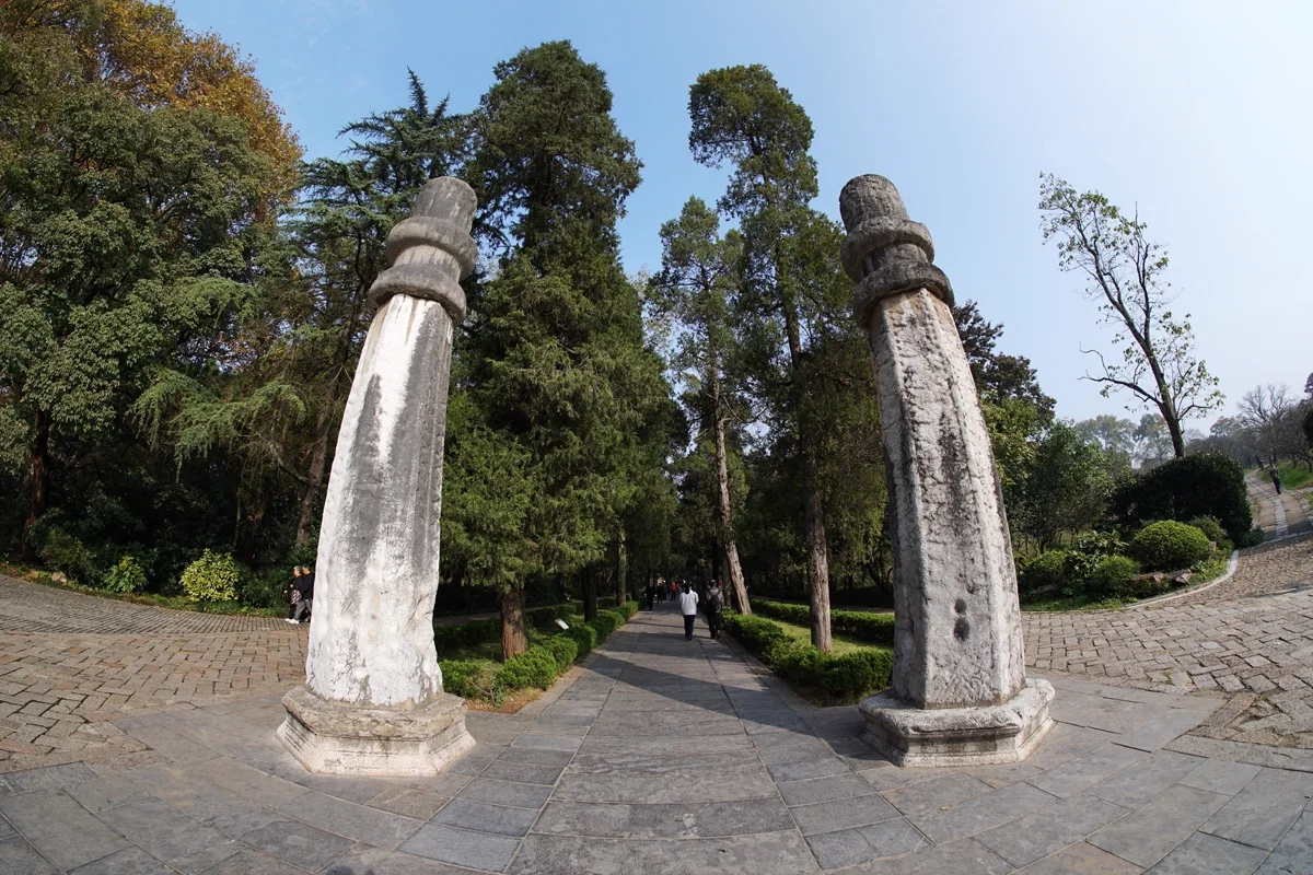 Stone path leading to Ming Xiaoling Mausoleum with ancient stone architecture and towering trees