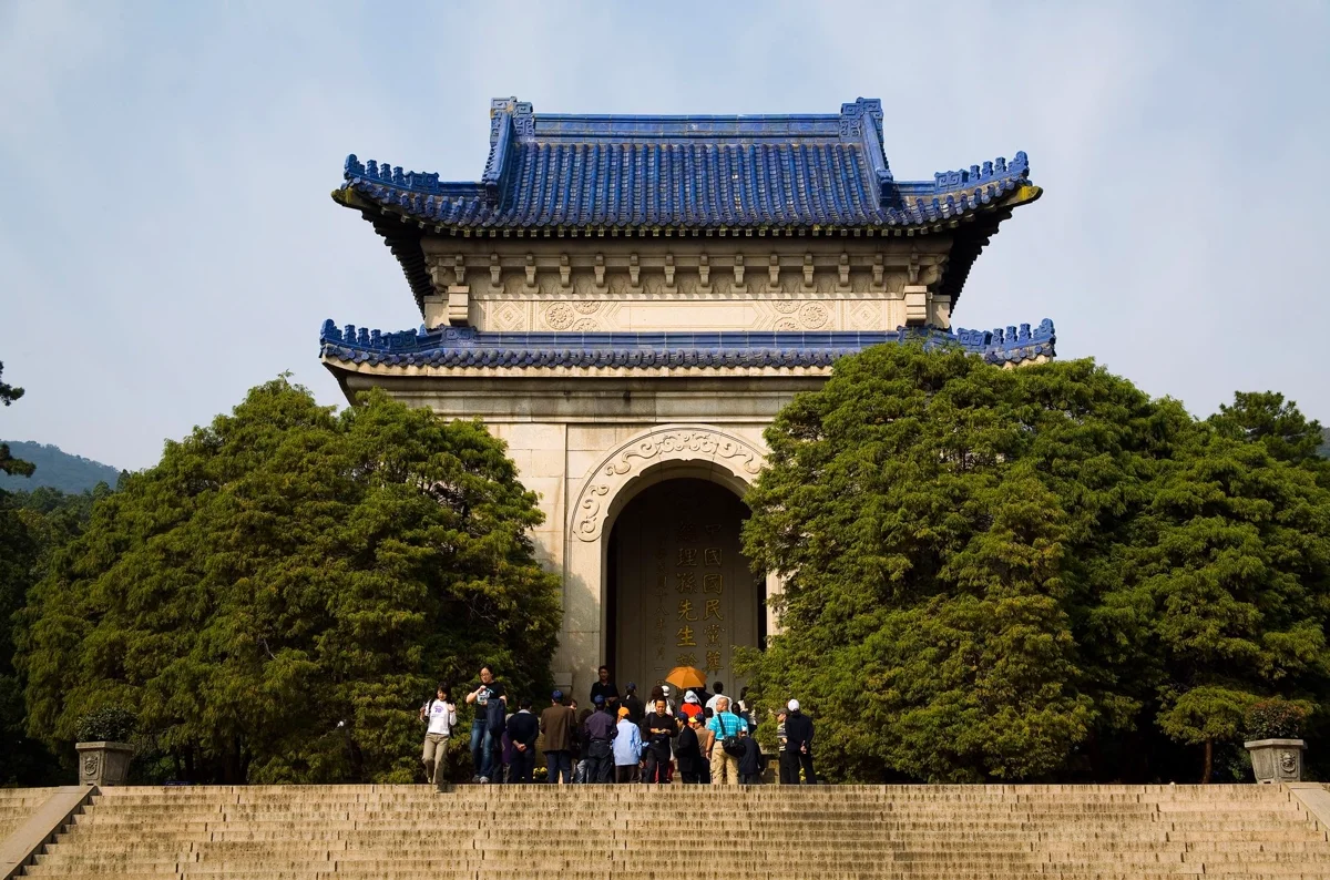 The iconic blue-tiled roof and wide stone steps of Sun Yat-sen Mausoleum surrounded by forest